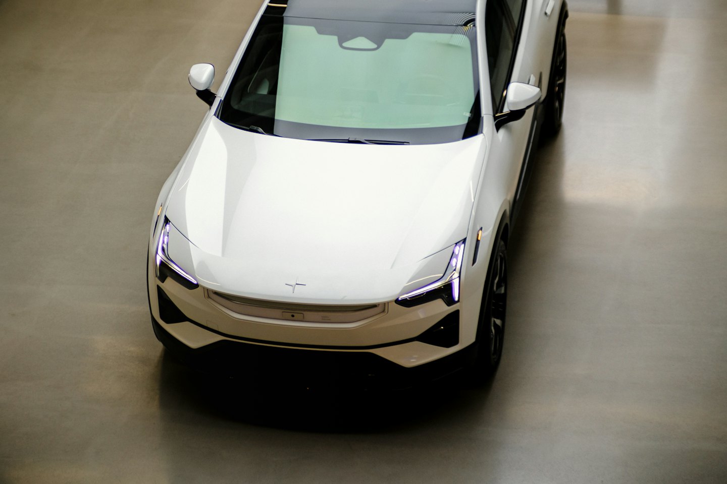 Biele elektrické auto zaparkované na leštenej betónovej podlahe showroomu.